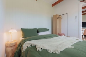 A bedroom with a bed, a bedside lamp, a wardrobe, and a chair.