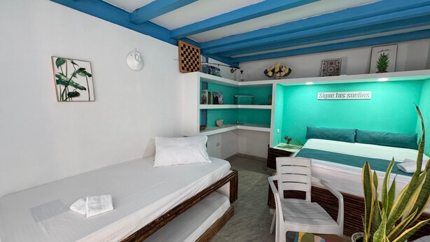 A room with a bed, a desk, and a chair. There are shelves with items on them, and a sign on the wall. - Beautiful private cabana with Jacuzzi, just one minute from the beach. (Tierra Bomba)