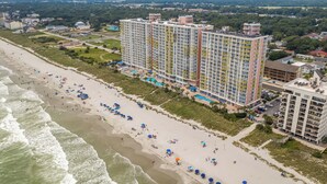 Un hotel de gran altura con varios balcones, ubicación frente a la playa y piscina.