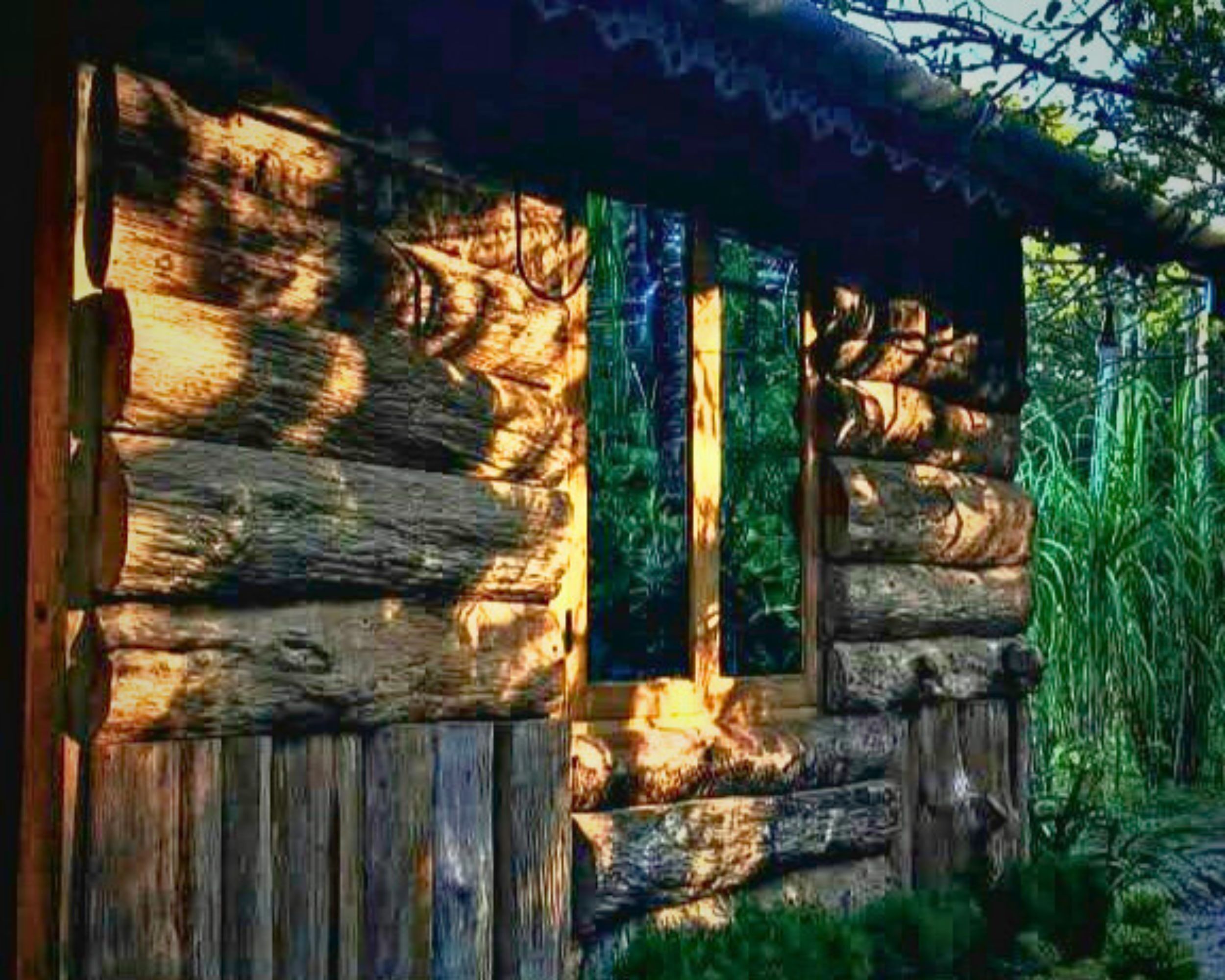 Une cabane rustique en rondins de bois, dotée d’une cheminée, d’une fenêtre et d’une porte.