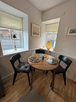 Un comedor con una mesa redonda de madera, sillas negras y posavasos estampados.