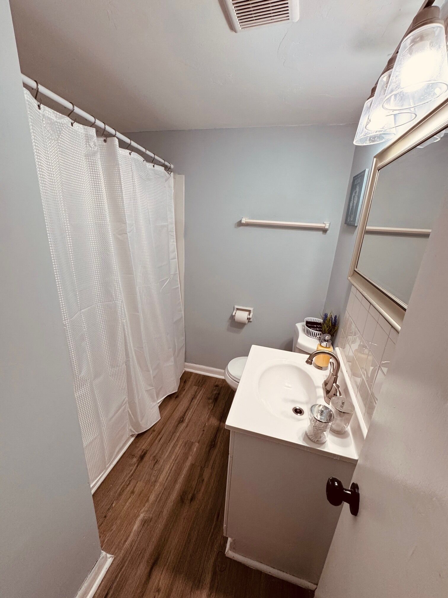 A bathroom with a white sink, a mirror, a toilet, and a shower curtain.
