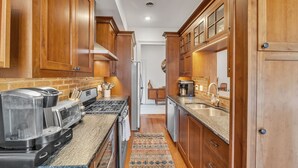 A kitchen with wooden cabinets, a coffee maker, a stove, and a refrigerator.