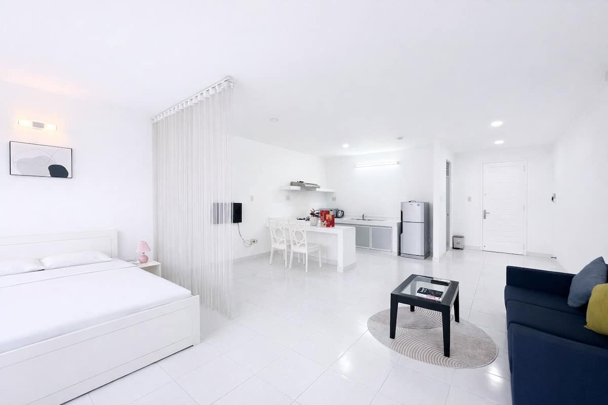 A modern, white-themed living area with a sofa, a coffee table, and a dining table with chairs.