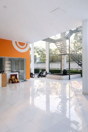 A spacious indoor area with a tiled floor, a reception desk, and a staircase leading to an upper level. - HD Garden Thu Dau Mot (Thu Dau Mot)