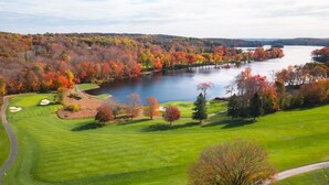 A golf course with a lake, trees, and a clear sky.