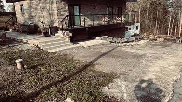 Una casa moderna de dos pisos con fachada de piedra, un balcón con mobiliario exterior y un camino de entrada.