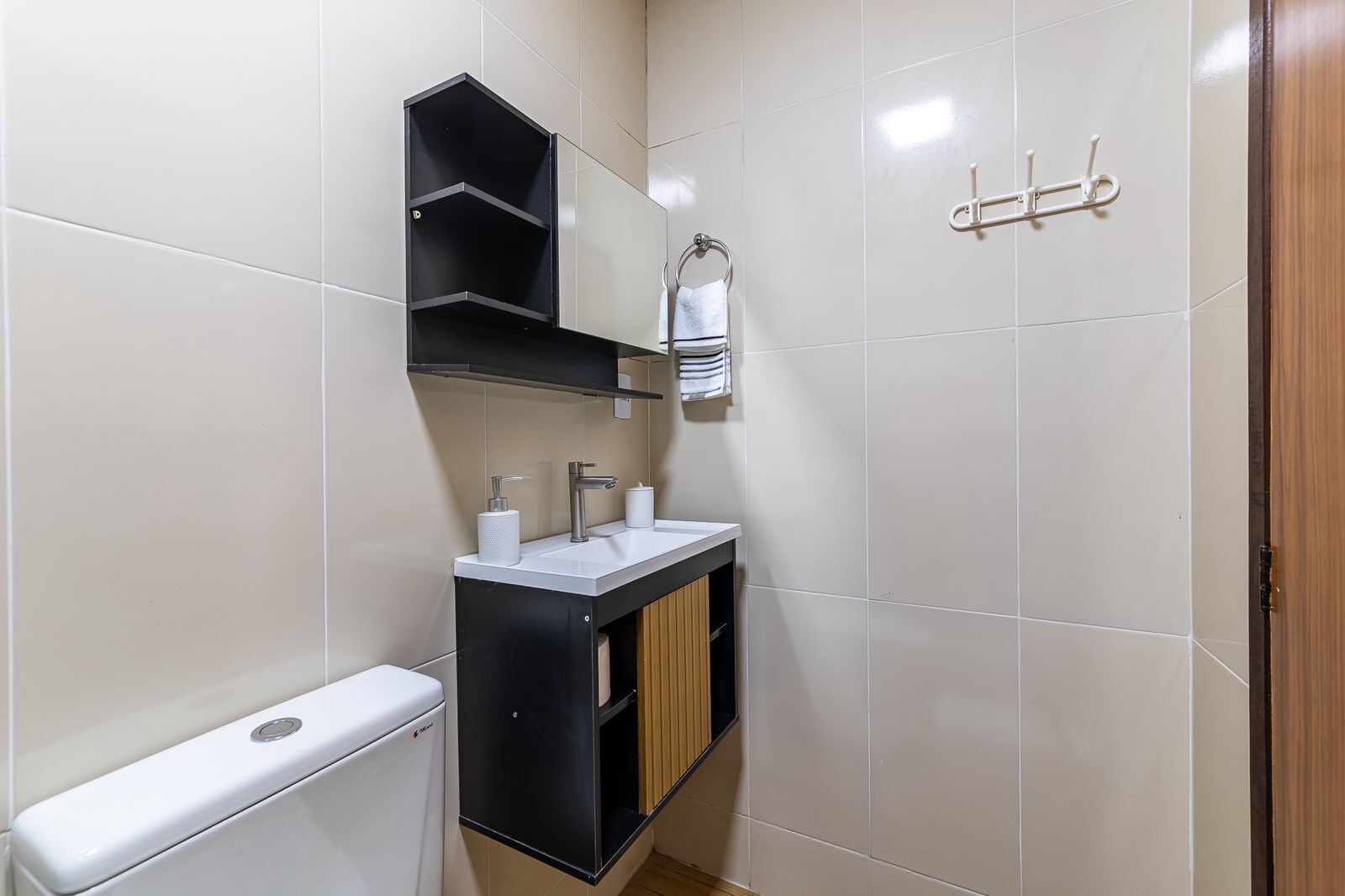 A bathroom with a toilet, a sink with a mirror, and a towel rack.