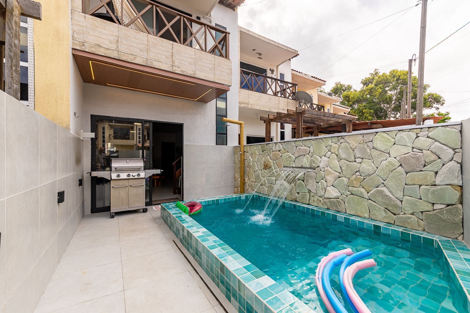 Une maison moderne dotée d’une piscine, d’un mur en pierre et d’un espace barbecue.