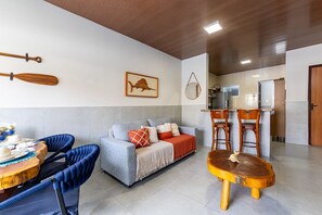 A modern living room with a sofa, chairs, a dining table, and a kitchen area.
