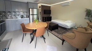Una cocina moderna con armarios grises, un refrigerador de acero inoxidable y un comedor con una mesa redonda y cuatro sillas.