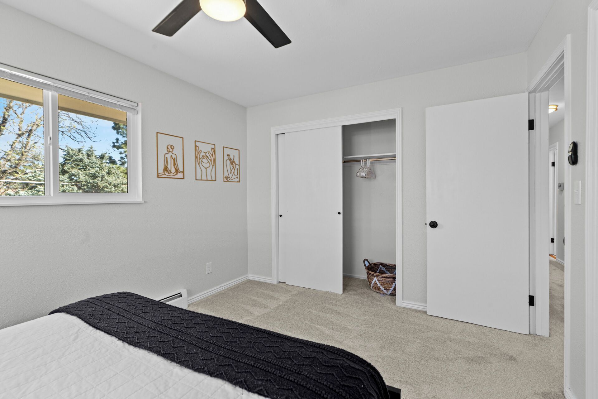 A bedroom with a bed, a closet, a window, and a ceiling fan.