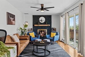 Ein modernes Wohnzimmer mit Kamin, zwei Sofas, einem Couchtisch und einem Deckenventilator.