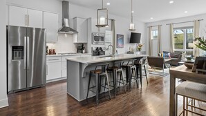 A modern kitchen with a central island, stainless steel appliances, and a bar seating area.