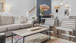 A modern living room with a sofa, chairs, a coffee table, and a staircase.