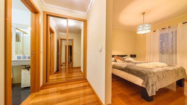 Un dormitori amb un llit, taules de nit i una finestra amb cortines.