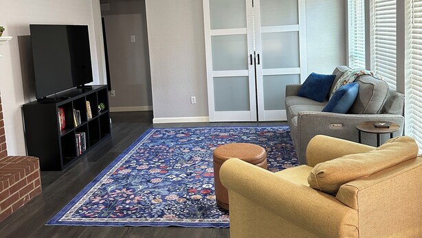 A living room with a ceiling fan, a TV, a sofa, a coffee table, and a patterned rug. - Lovely 3-bedroom house with AC in peaceful Mansfield (Mansfield)