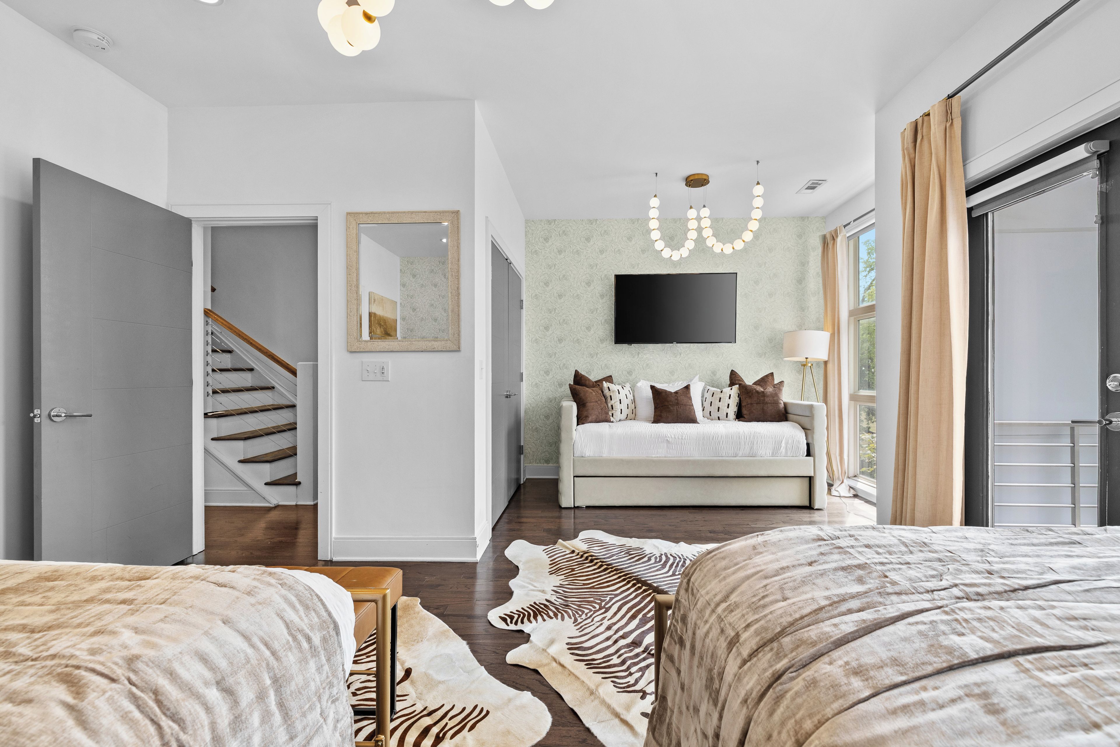 Une chambre à coucher moderne avec un lit, un canapé, une télévision et un escalier.