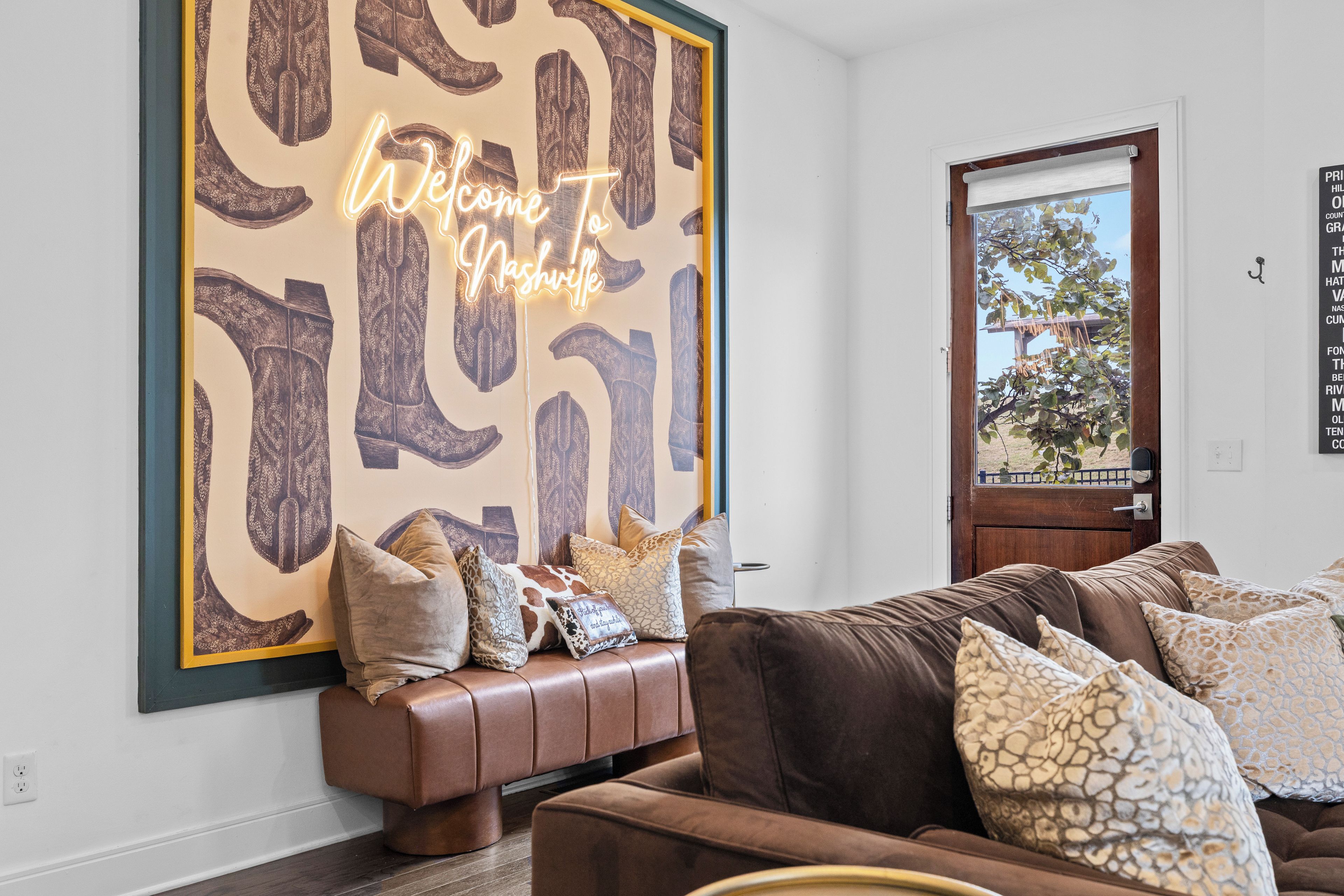 A living room with a large wall art piece, a leather sofa, and a bench with cushions.