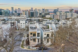 A modern residential area with high-rise buildings and a city skyline in the background. - Walk to Broadway / Rooftop w/ City Views / 14 beds (Nashville)