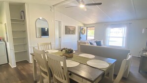 A dining area with a wooden table, white chairs, and a ceiling fan.