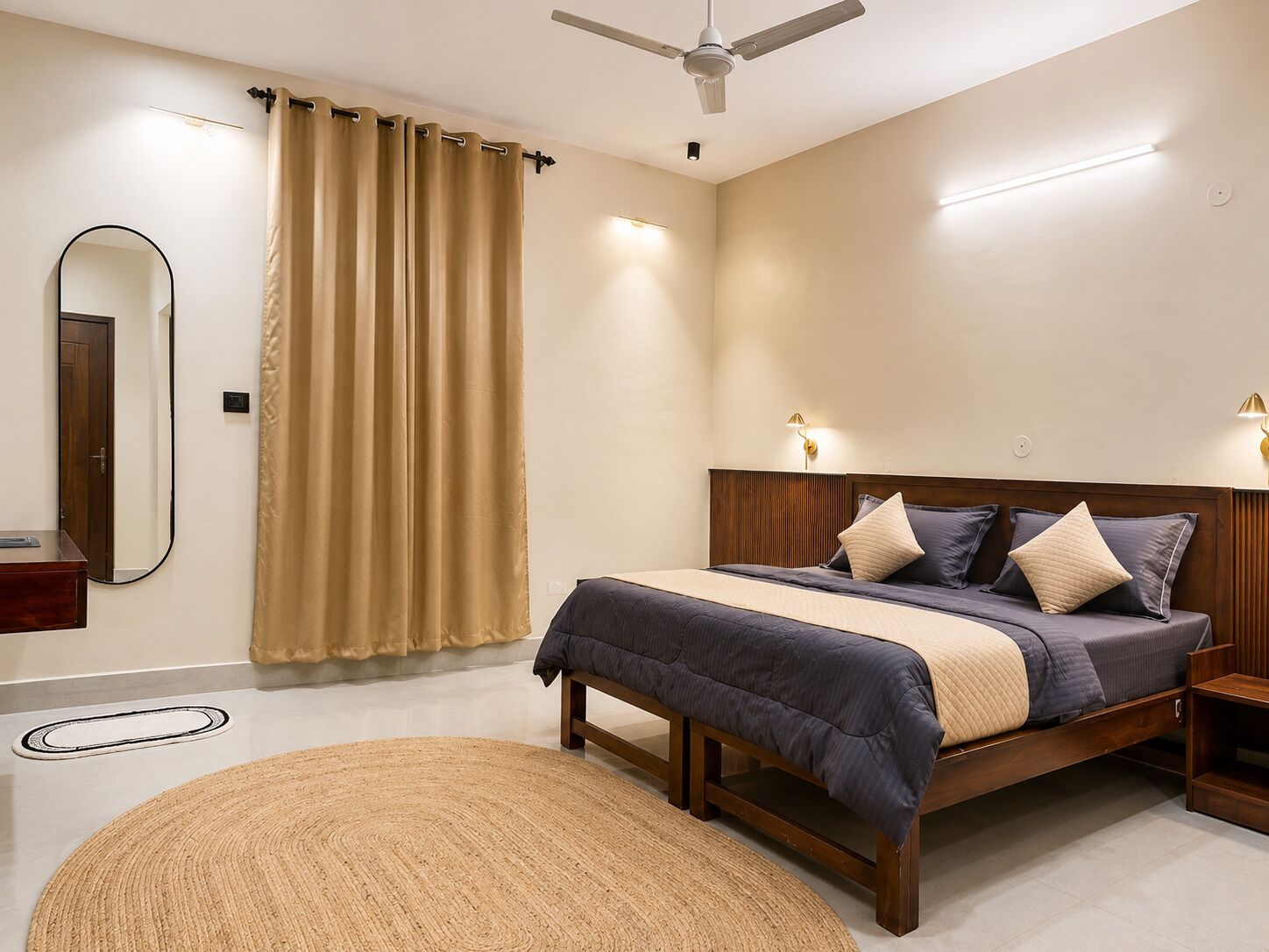 A bedroom with a bed, bedside lamps, a ceiling fan, and a large mirror.