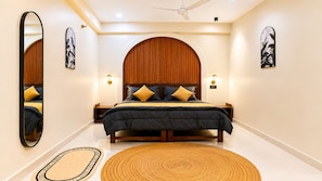 A bedroom with a bed, nightstands, a mirror, and artwork on the walls. - Casa garden Aamwala (Dehradun)