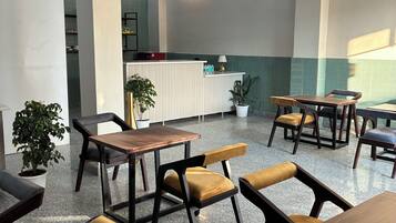 Un espace intérieur spacieux, doté de plusieurs tables et chaises, d’un comptoir d’accueil et de plantes en pot.
