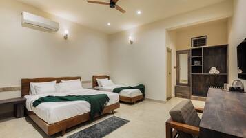 A hotel room with two wooden beds, a ceiling fan, a built-in wardrobe, and a dining area with a table and chairs.