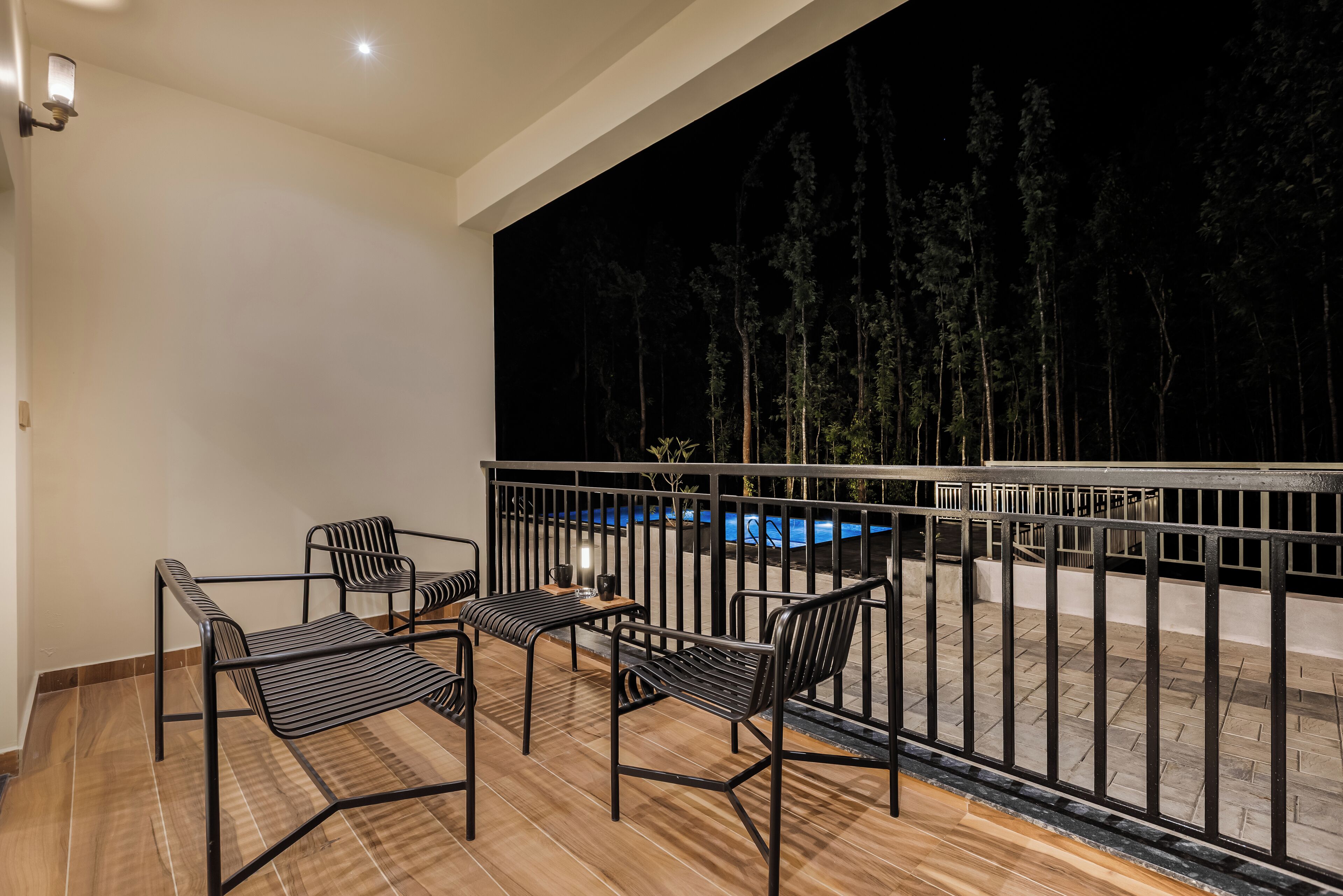 A balcony with a pool view, metal chairs, and a wooden floor.