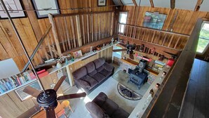 L’intérieur d’une cabane comprend un espace salon surélevé, une cheminée et un ventilateur de plafond.