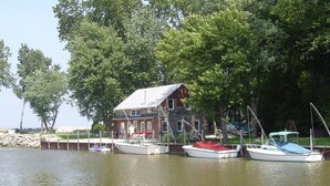 Une maison en bois avec un quai, deux bateaux et un mur en pierre.