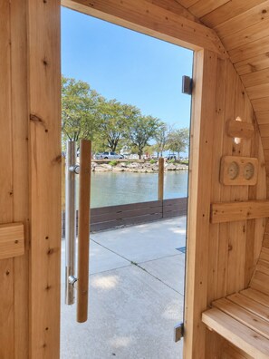 A wooden sauna with a view of a lake and trees.