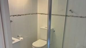 A modern bathroom with a glass shower enclosure, a toilet, and a sink. - Pearly shells central Nelson Bay. (Nelson Bay)
