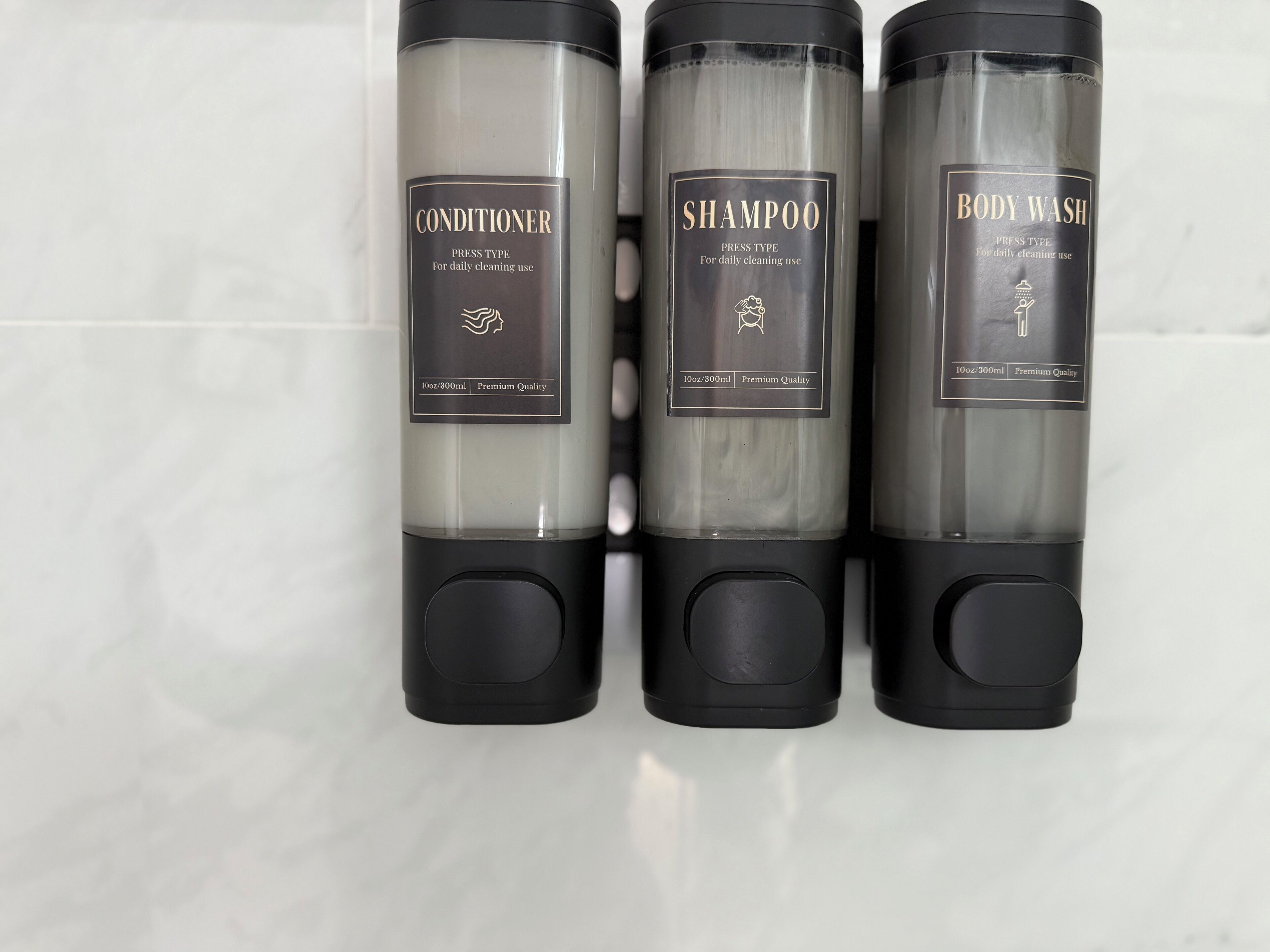 Drei Flaschen Körperpflegeprodukte: Conditioner, Shampoo und Duschgel, jede mit Volumen- und Qualitätsangabe versehen.