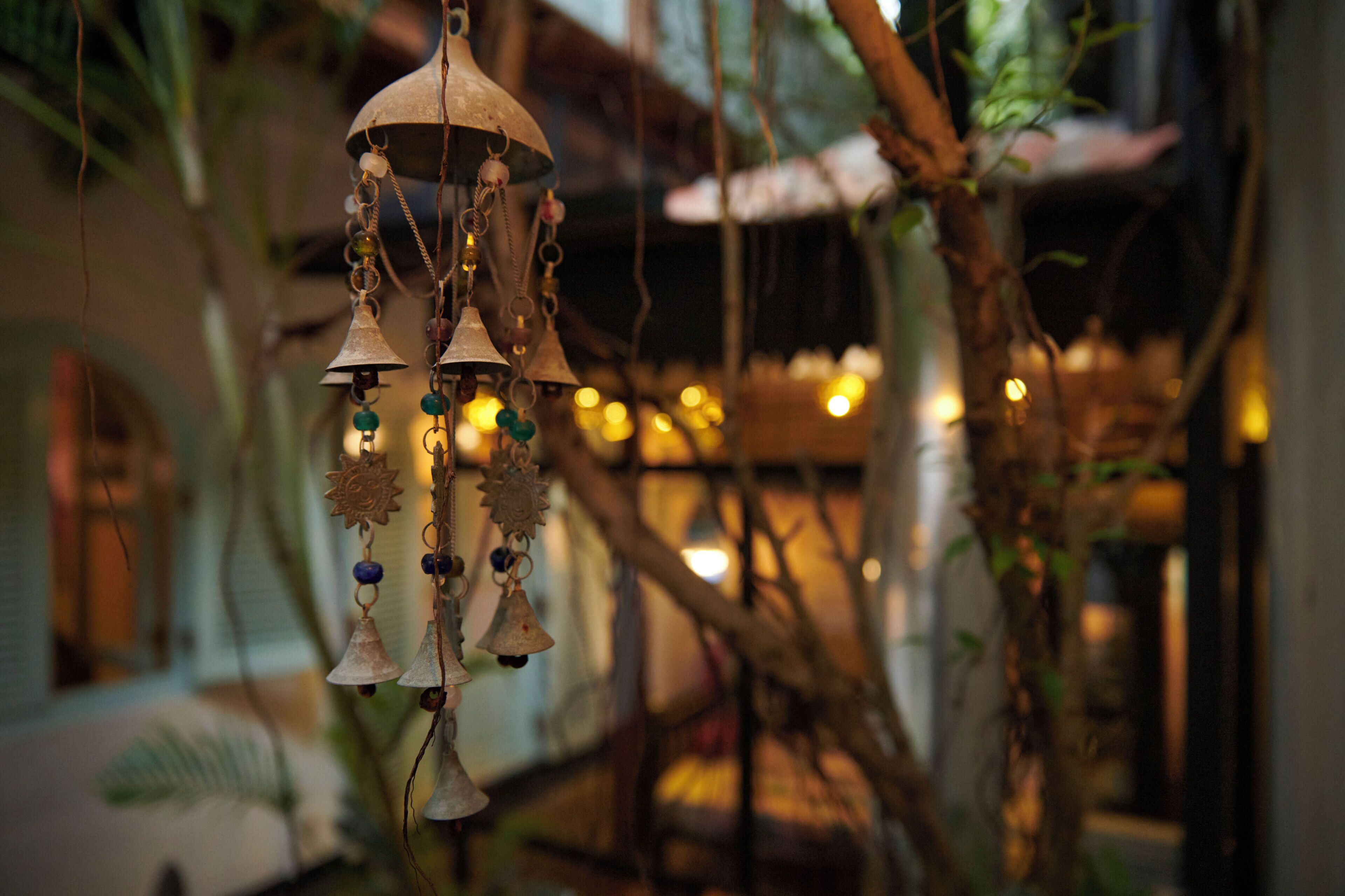 A wind chime with bells and beads hanging from a branch.