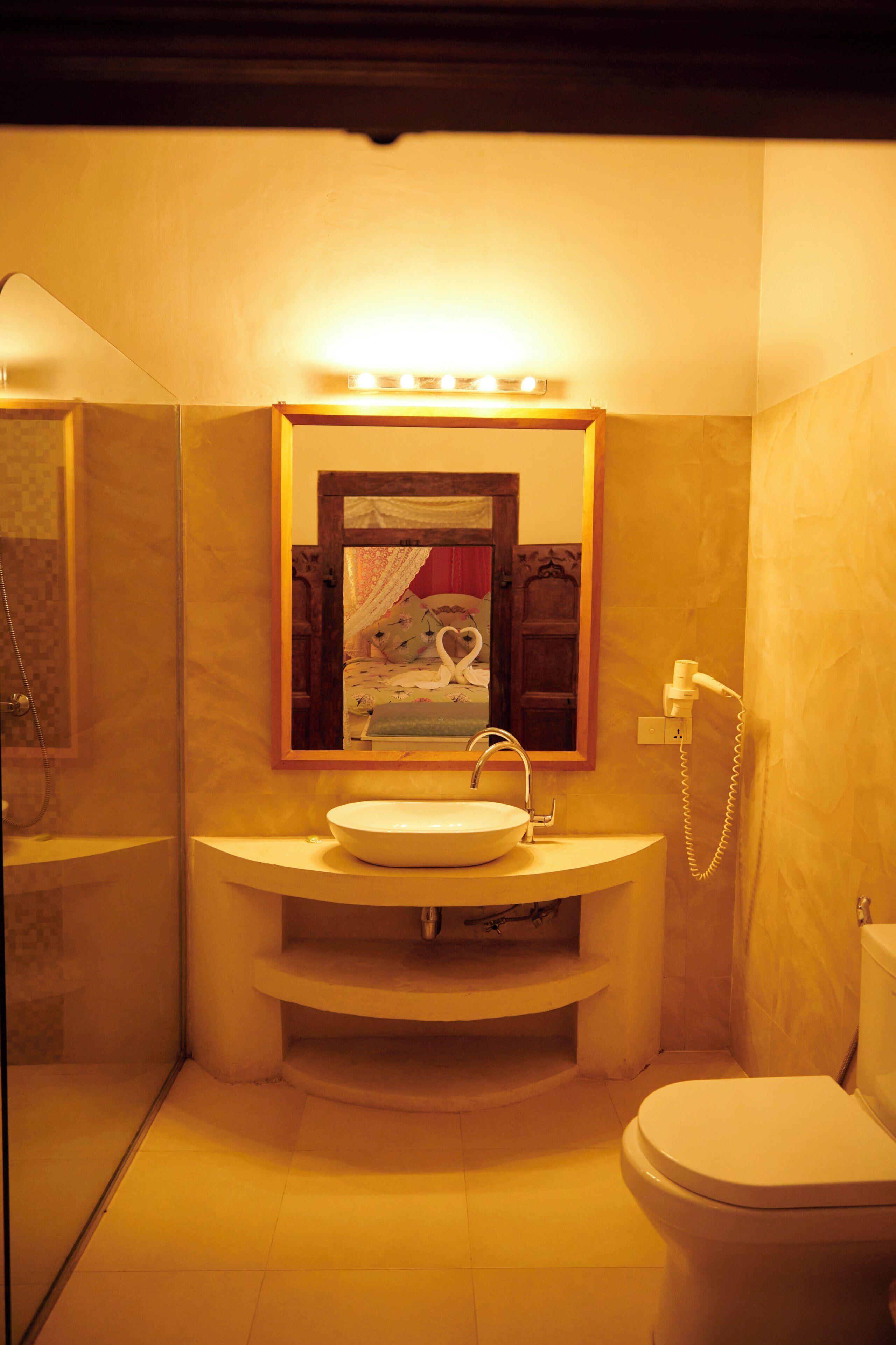 A bathroom with a sink, mirror, and toilet.