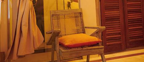 A room with a wooden chair, a wooden door, and a curtain.