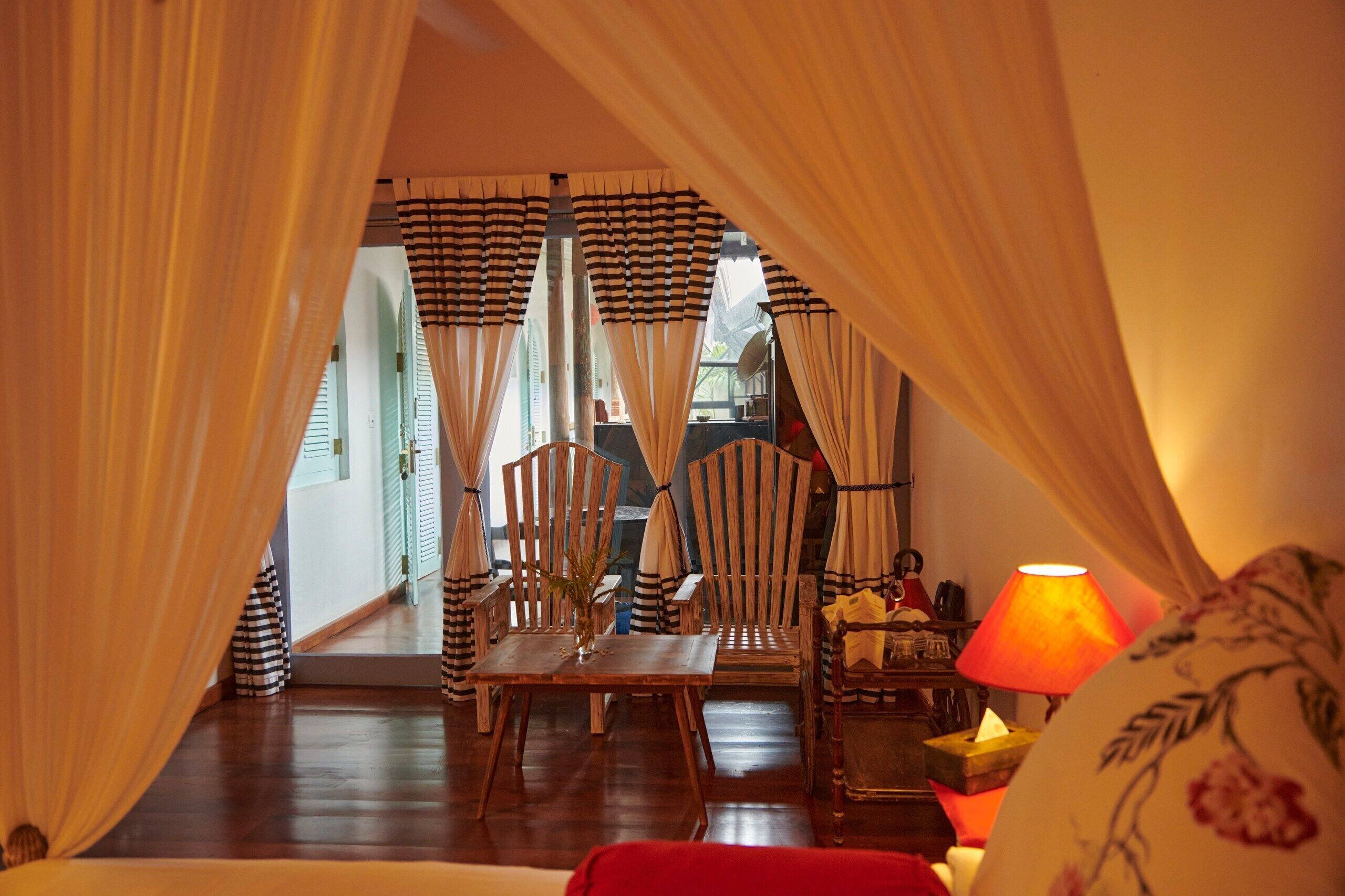 A room with a wooden dining table, striped curtains, and a lamp.
