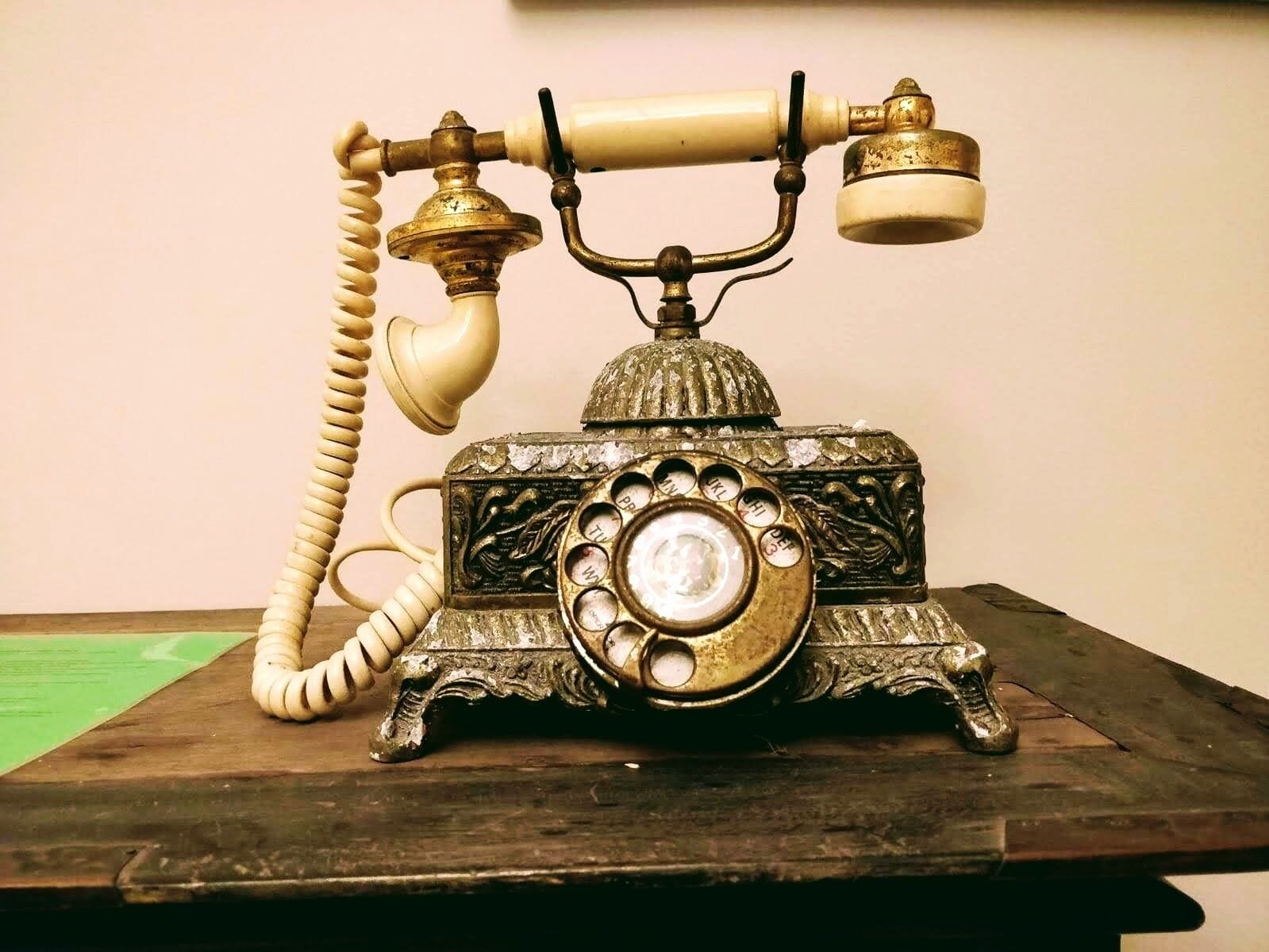 An antique rotary dial telephone on a wooden surface.