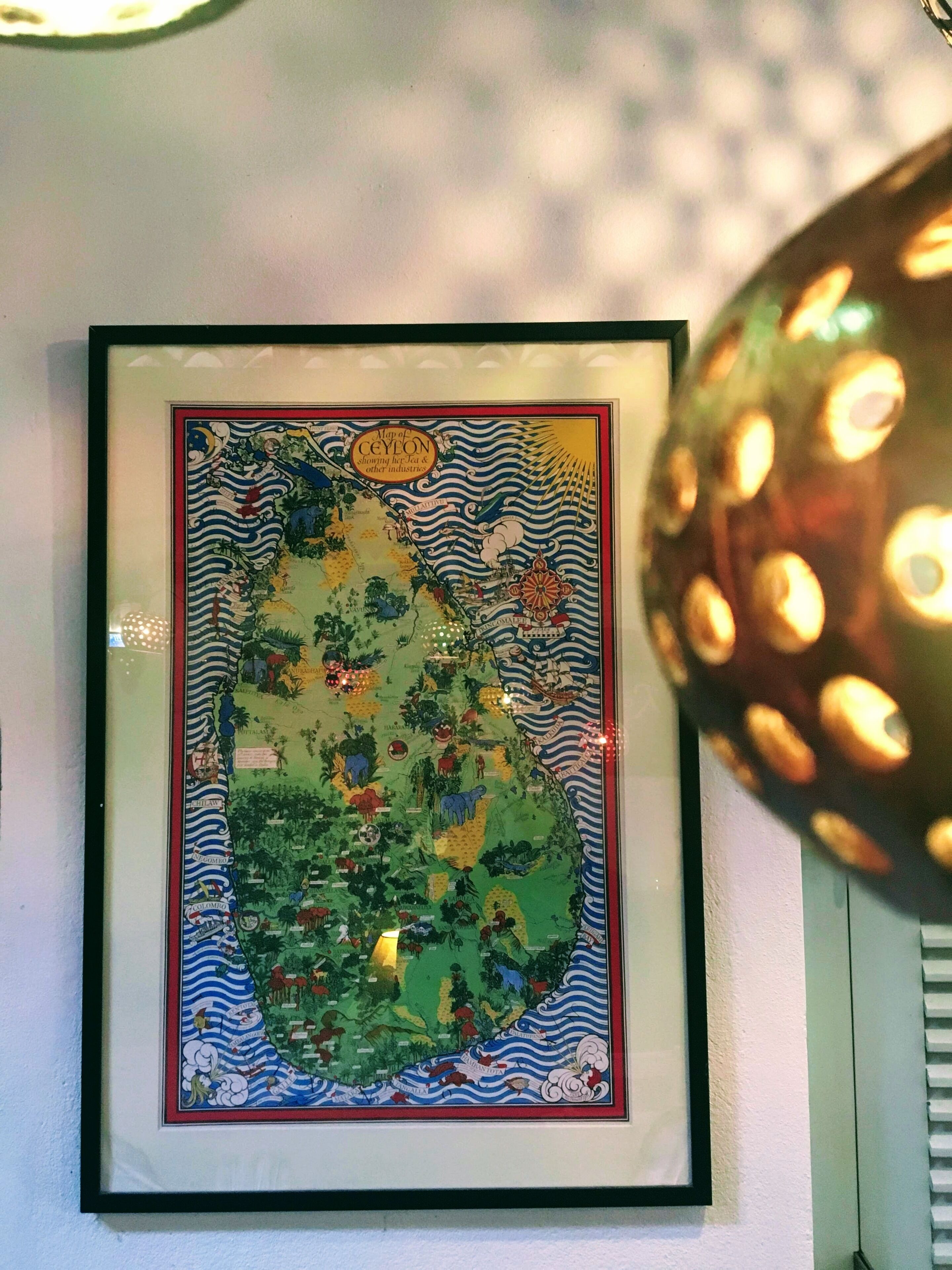 A framed map of Ceylon with a decorative border.