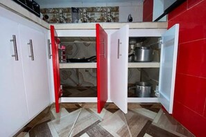 A kitchen with white cabinets, a red door, and a tiled backsplash. - Family Apartment in Ibagué - Comfort, Tranquility and Excellent Location (Ibagué)