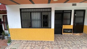 Un edificio con facciata giallo e bianca, inferriate nere alle finestre e pavimento piastrellato.