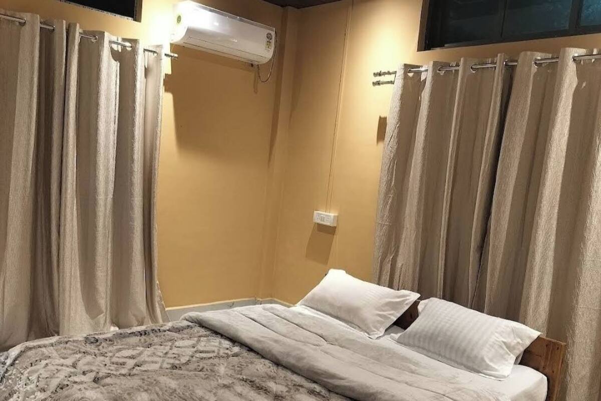 Un dormitorio con cama, cortinas, un equipo de aire acondicionado y un cabecero de madera.