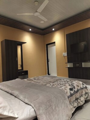 A bedroom with a bed, a wardrobe, a television, and a ceiling fan. - Orchid Guest House (Pakke Kessang)