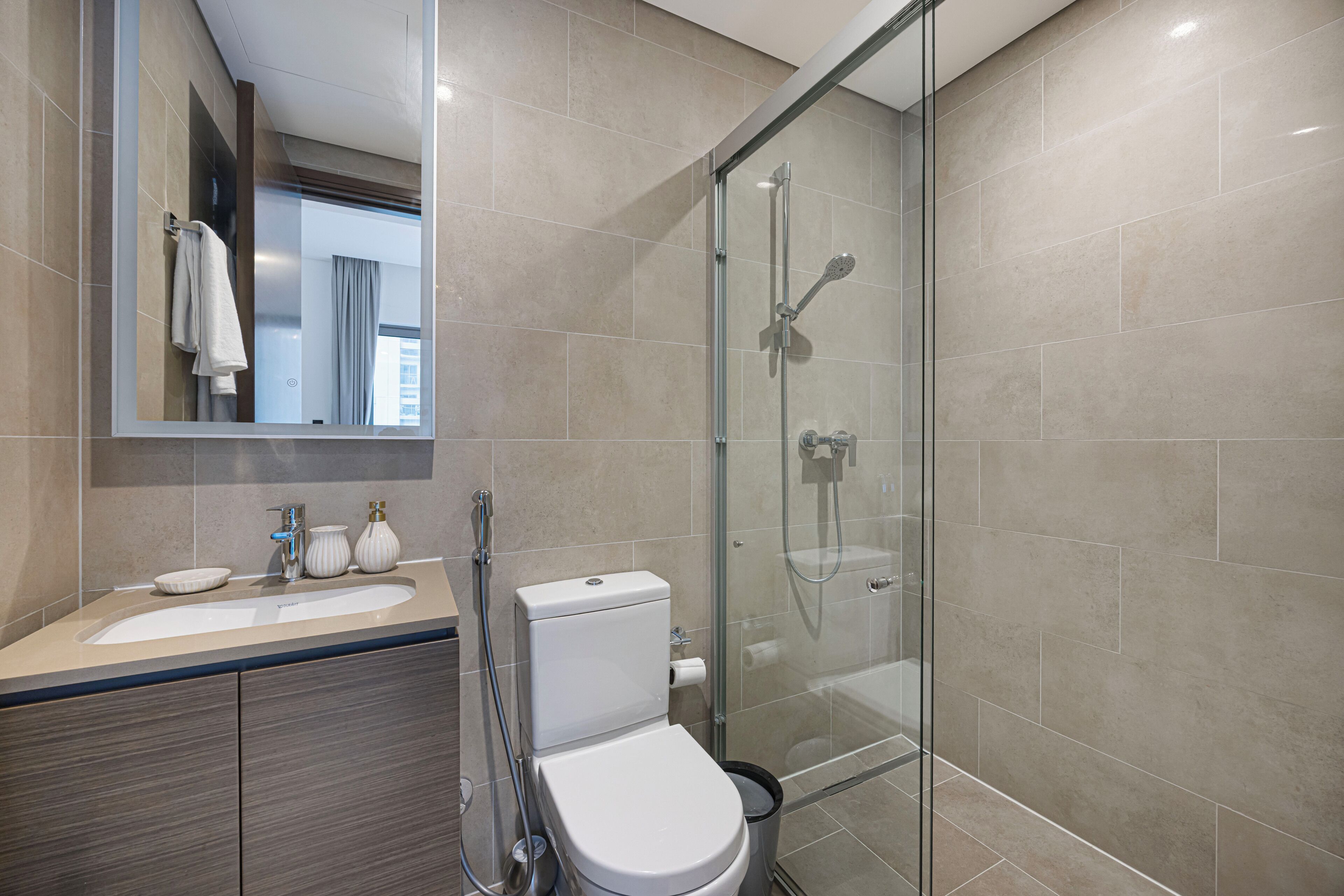 A modern bathroom with a glass-enclosed shower, a sink with a mirror, and a toilet.