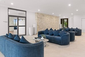 A modern living room with a sectional sofa, a coffee table, and a stone accent wall. - Luxury 3-Bedroom Stay with City and River View (Brisbane City)