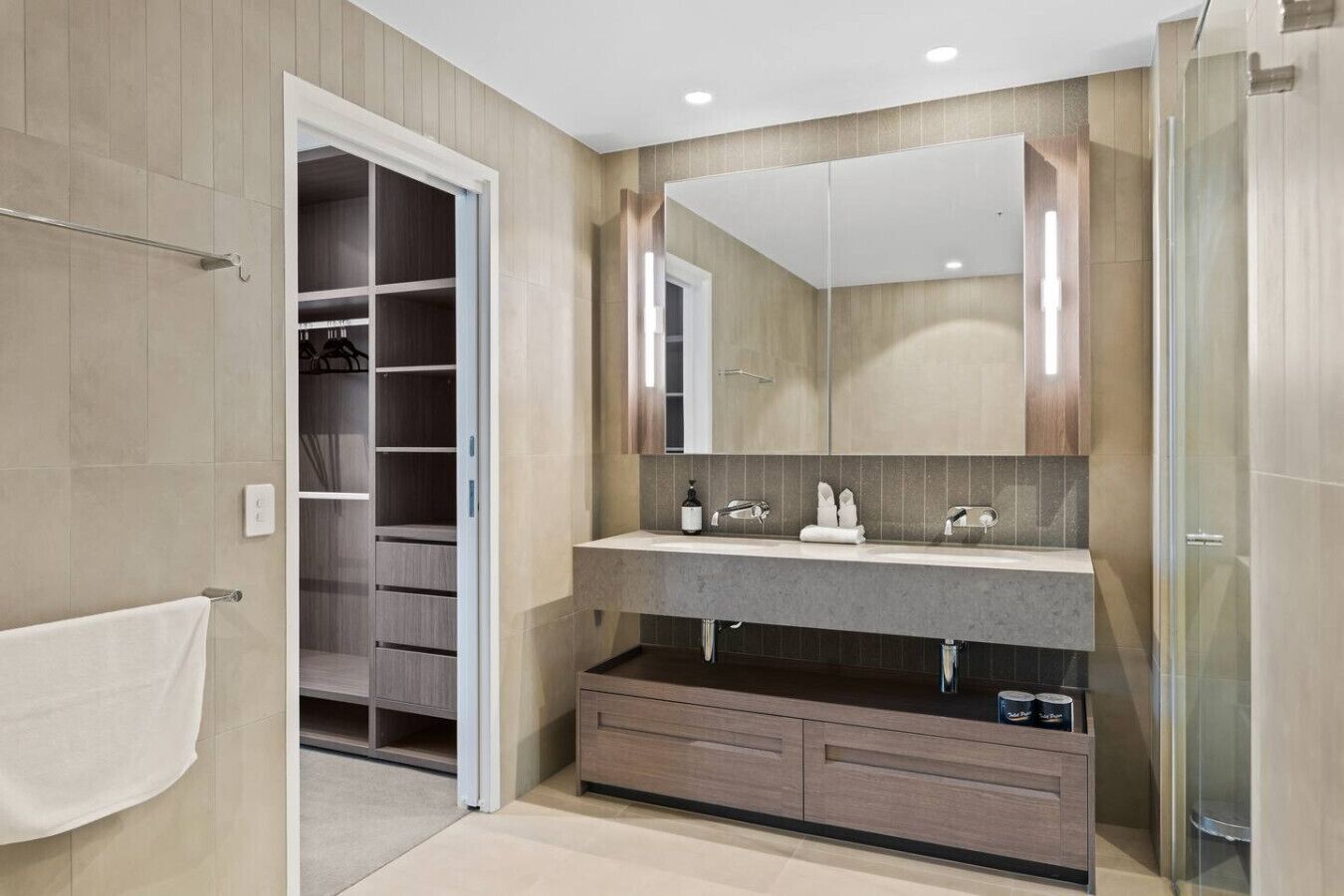 Une salle de bain moderne avec un dressing, un grand miroir et une cabine de douche.