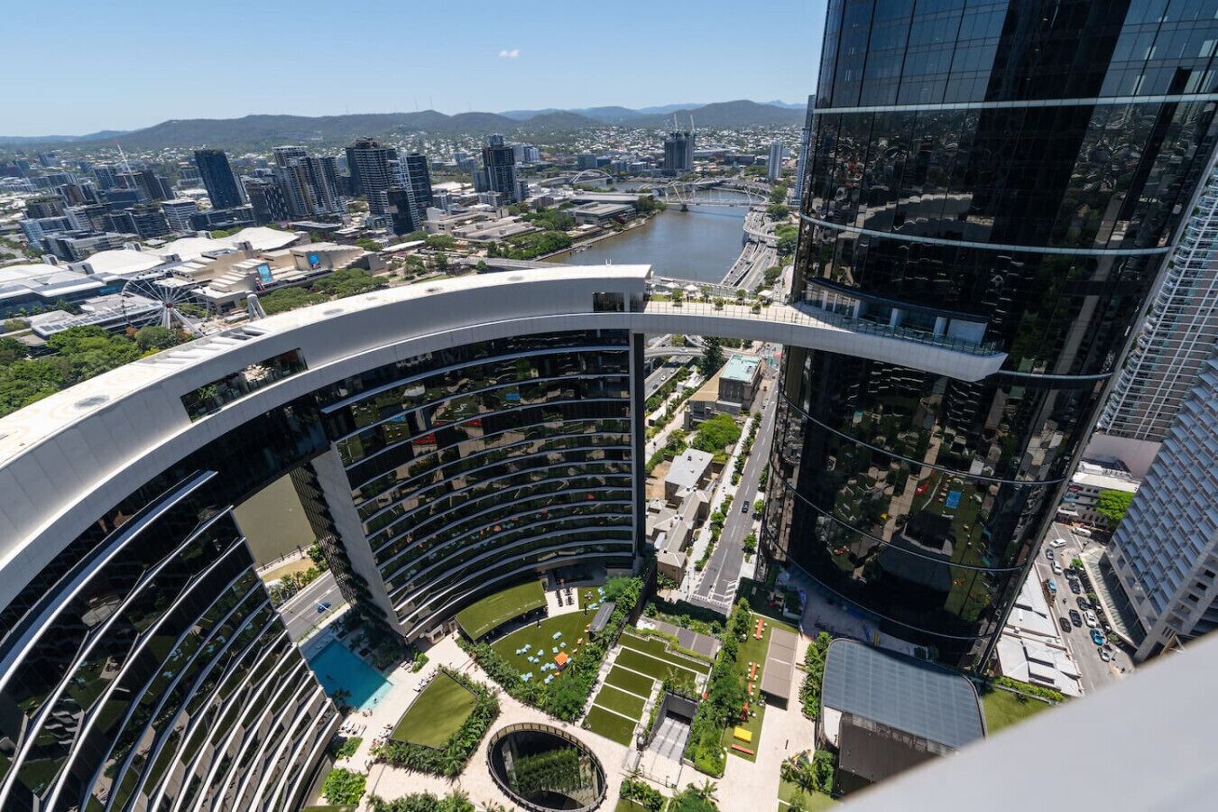 A high-rise building with a curved exterior and a rooftop garden.
