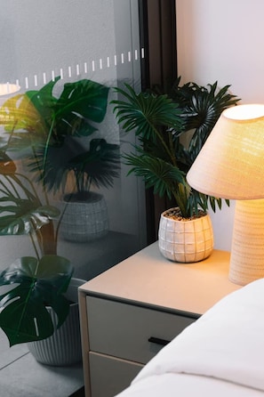 A bedside table with a lamp, a potted plant, and a drawer. - Cozy 1Bedroom Near Casino Luxe Tower&South Bank (Brisbane City)